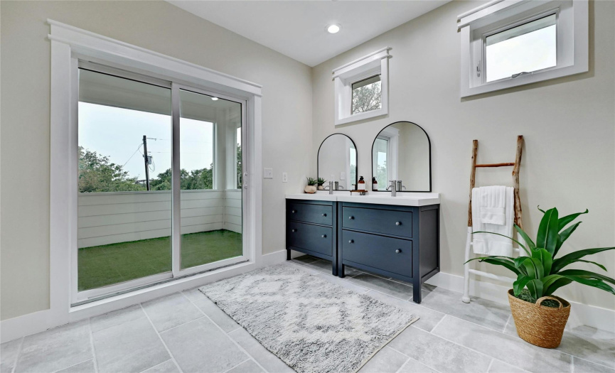 The stylish primary bathroom has a painted blue vanity, large glassed-in shower, and sliding door access to the private deck that spands the second floor.