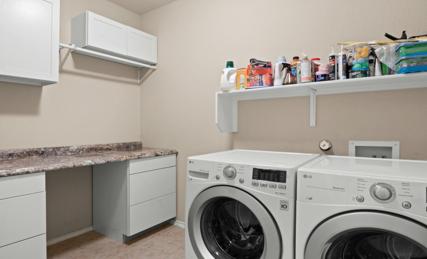 Spacious laundry room with build in cabinets and counter