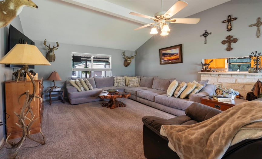 The spacious living room impresses with its high ceilings, ceiling fan, and plush carpeting, creating an inviting space for relaxation and entertainment.