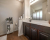 The primary bathroom includes a large vanity and wood-like tile flooring throughout.