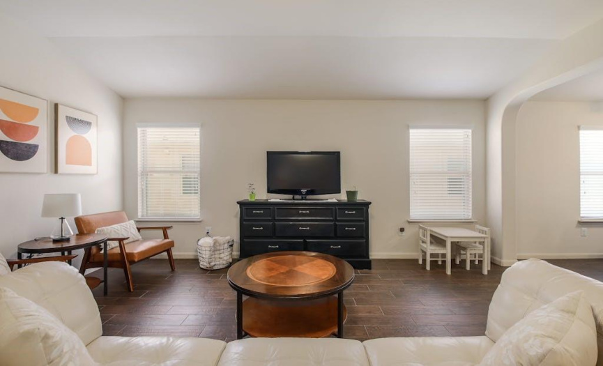Great natural light, wood-like tile flooring, and high ceilings in the spacious living room.