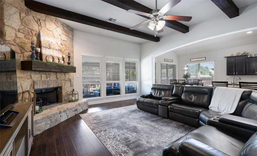 Large living area with the stone-to-the-ceiling fireplace, raised hearth; exposed ceiling beams and open to both kitchen and dining areas.