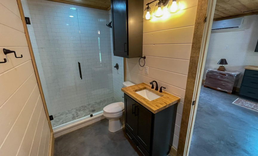 Bathroom: Walk-in Tiled Shower with glass door, concrete floors, wood ceilings, butcher block wood countertops, painted wood walls and wood doors.