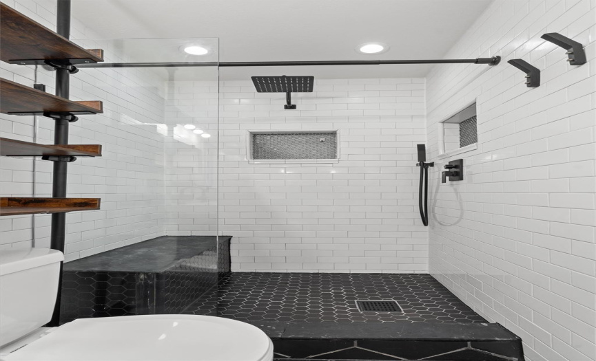 Inside the shower, white subway tile adds a classic touch, contrasting beautifully with the dark flooring. A glass sliding door adds a touch of sophistication while allowing natural light to fill the space.