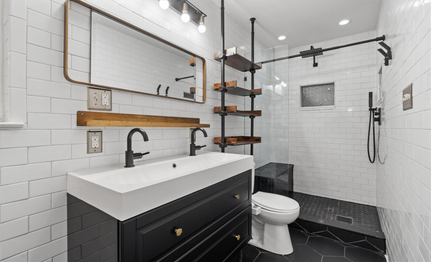 Step into luxury with this stylish bathroom featuring a floating vanity that exudes modern elegance. The dark octagon tile flooring seamlessly transitions into the shower, creating a sleek and cohesive look.