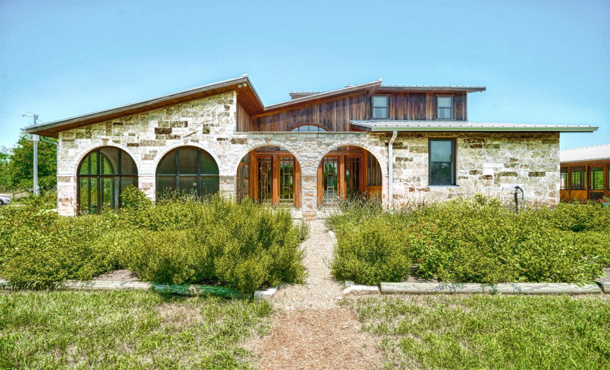 Mediterranean style arches over courtyard with established Texas native xeriscaping