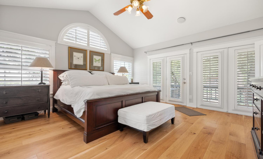Beautiful and serene primary bedroom adorned with plantation shutters (and right out this french door is the walk way to the covered back porch and pool)