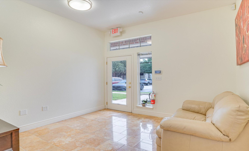 Large travertine tile stone flooring with glass front door that brings in natural light are features of this receiving room.