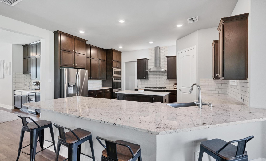 Fit your resident chef; your kitchen features a peninsula breakfast bar, granite countertops, an island, built-in microwave, double ovens, a tile backsplash, and a gas cooktop.