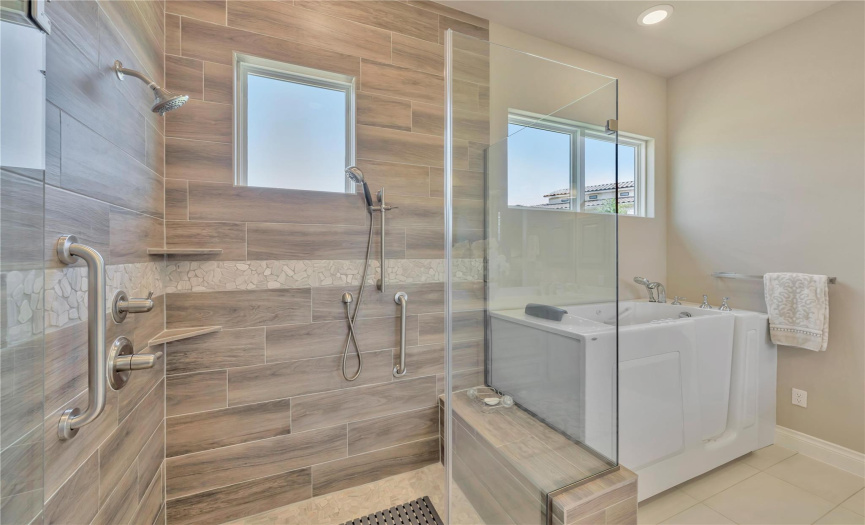 The walk-in shower includes a bench seat, upgraded tile, grab bars and hand held and stationary shower head.