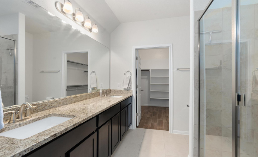 Primary bathroom boosts dual vanities with lots of cabinet space, a large walk in shower, and an even larger walk in closet. 