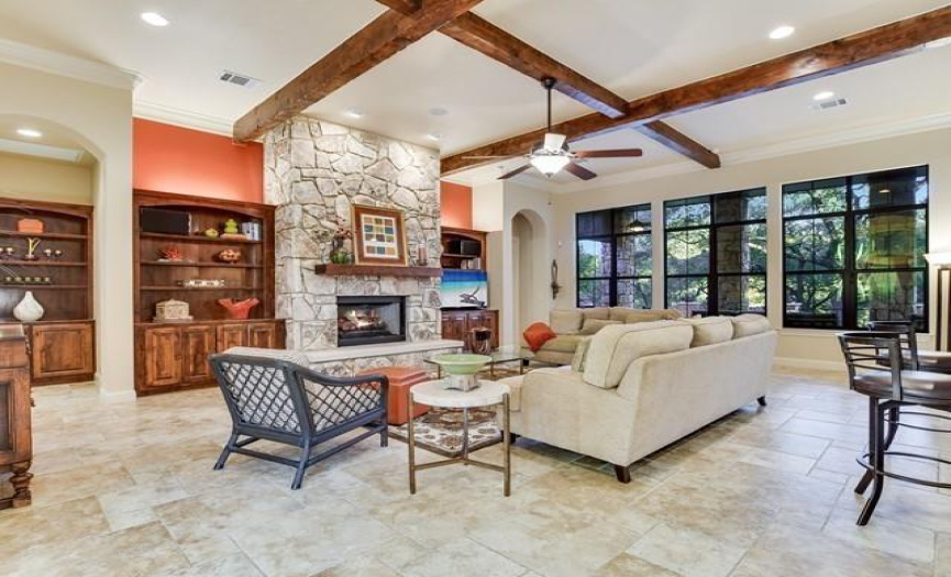 The great room features a towering fireplace meticulously crafted with local Georgetown cavestone and limestone. Hearth and chimney are flanked by tailor-made knotty Alderwood bookshelves.
